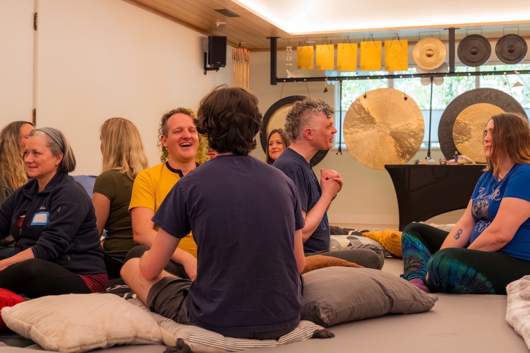 Pairs of participants face one another and sit on low cushions.