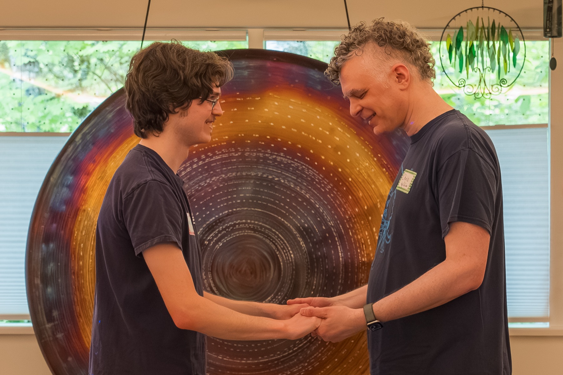 Two participants stand, smiling and holding hands quietly.