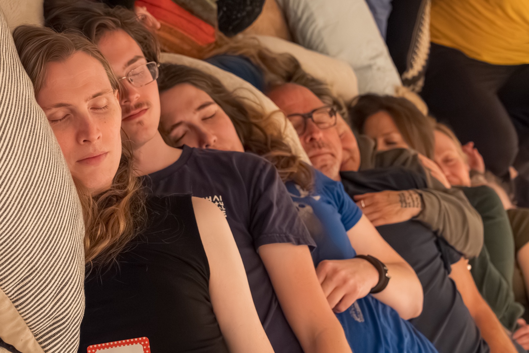 A row of seven participants lie on their sides facing the same direction and spooning.