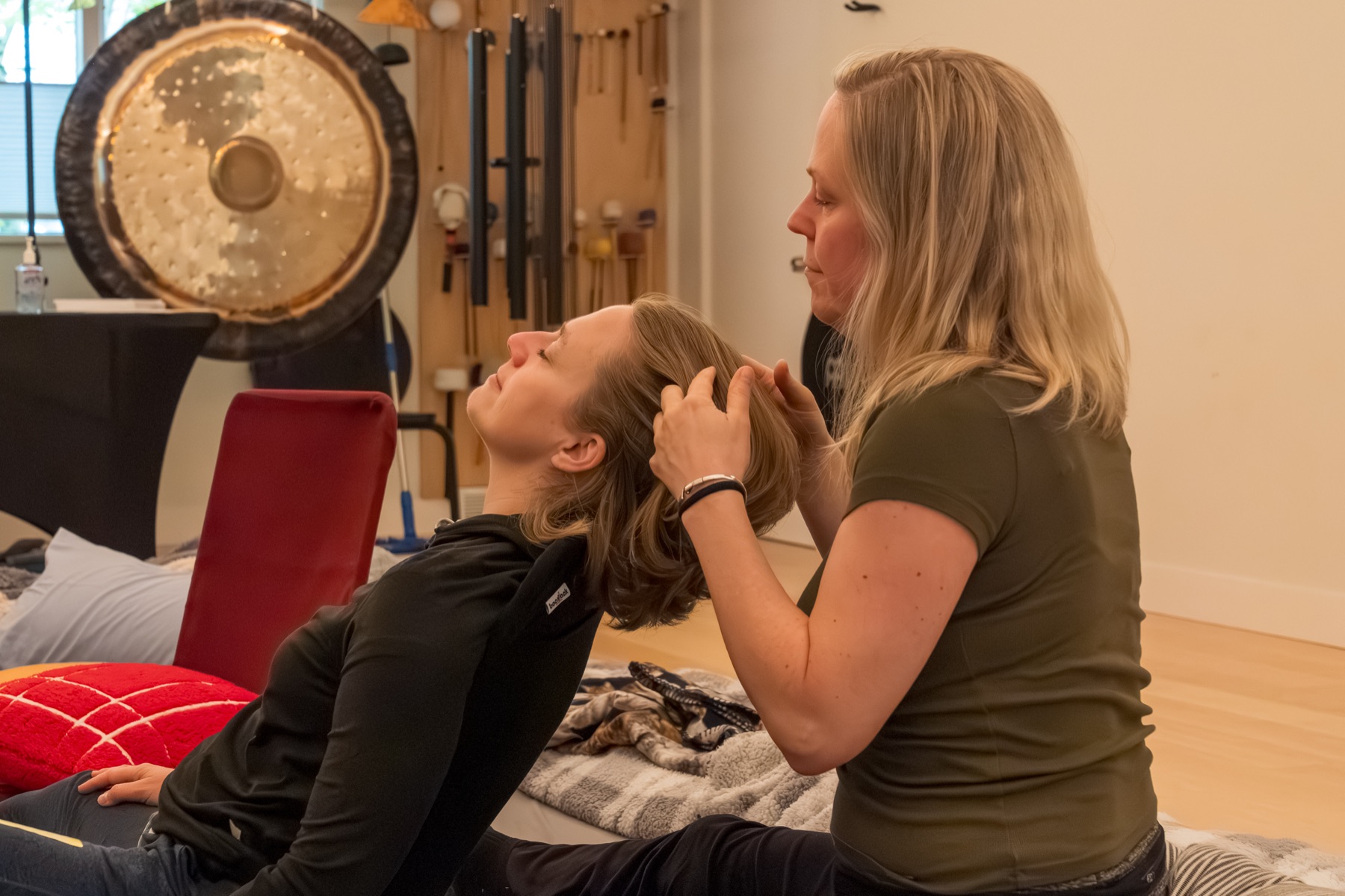 Two participants connect: one rests in a recline while the other gently combs and plays with their hair.